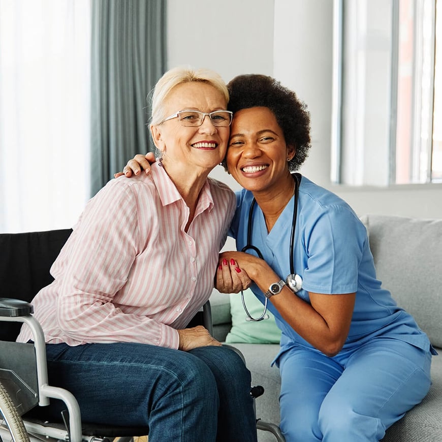 Female nurse and older woman patient smiling directly at camera